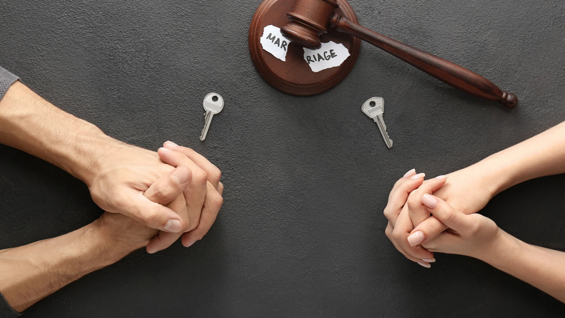 Kadın ile erkek karşılıklı oturmuş ve her ikisi de ellerini birleştirmiş ve masaya koymuş .Ellerinin yanında birer tane anahtar ve tam ortada bir tokmak var