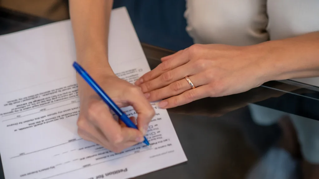 Bir kişi elindeki kalemle boşanma dilekçesini imzalıyor