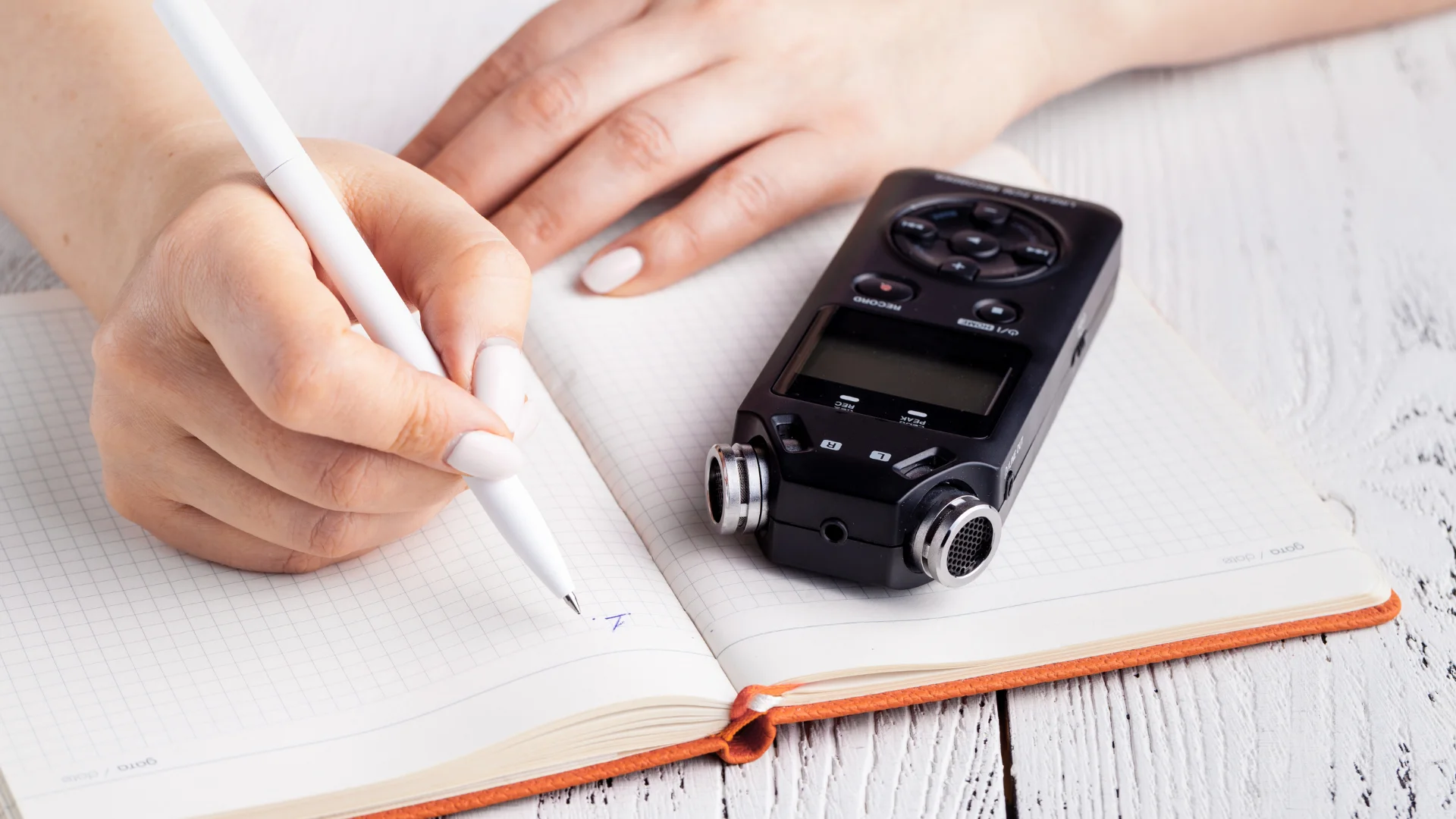 Bir kişi deftere birşeyler yazıyor ve defterin bir köşesinde de kayıt cihazı var