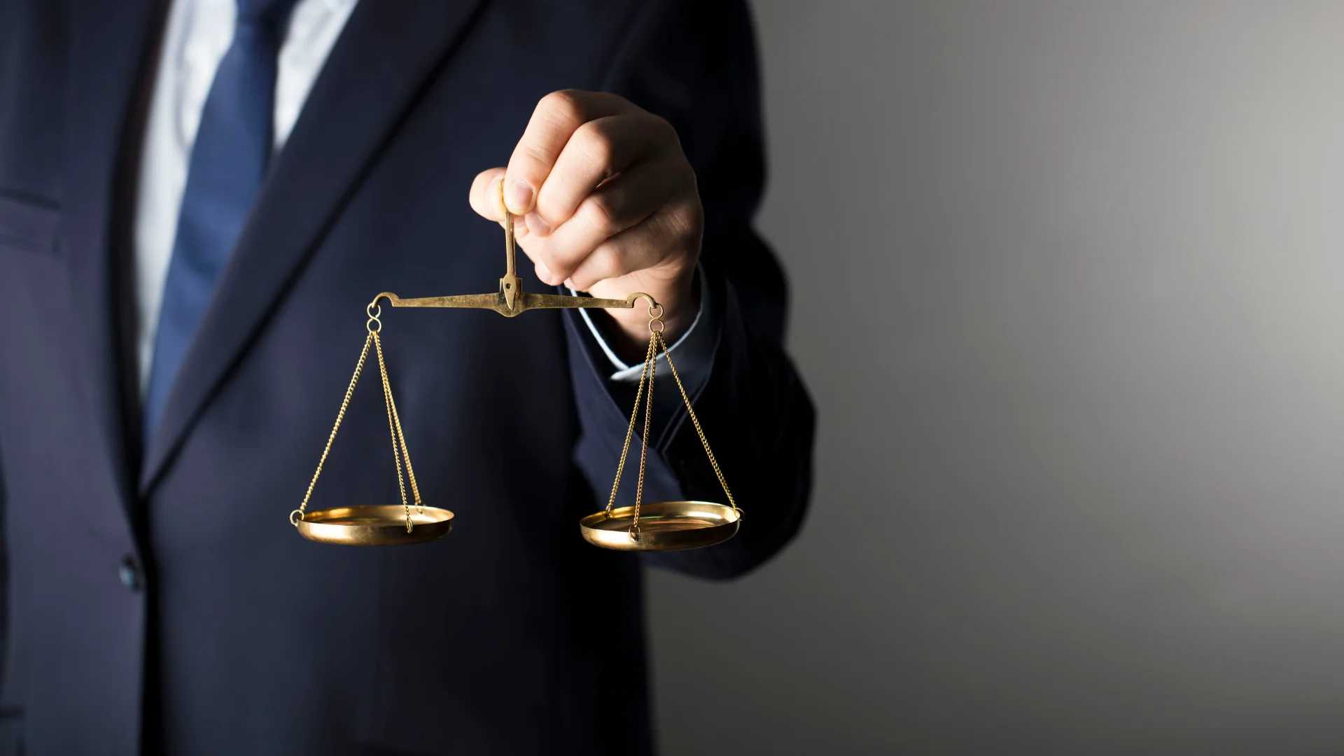 Takım elbilesi bir kişi ve elinde hukuk terazisi var