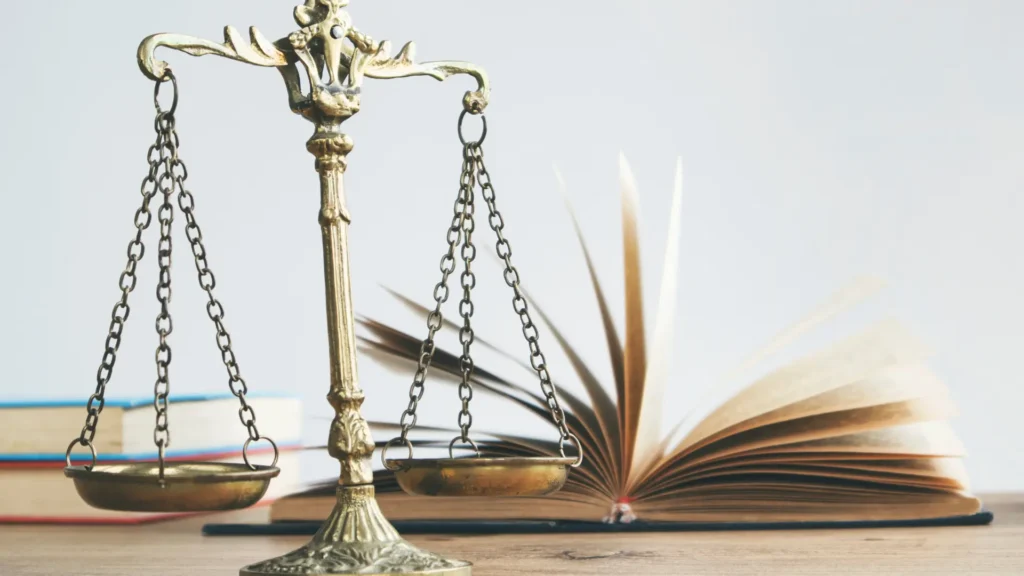 Hukuk terazisi ve arkasında sayfaları dalga dalga açılan bir kitap var