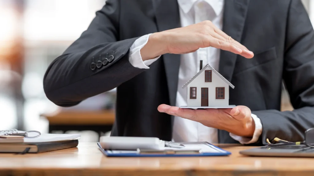 Takım elbiseli bir kişi eline maketten ev önündeyse evraklar var